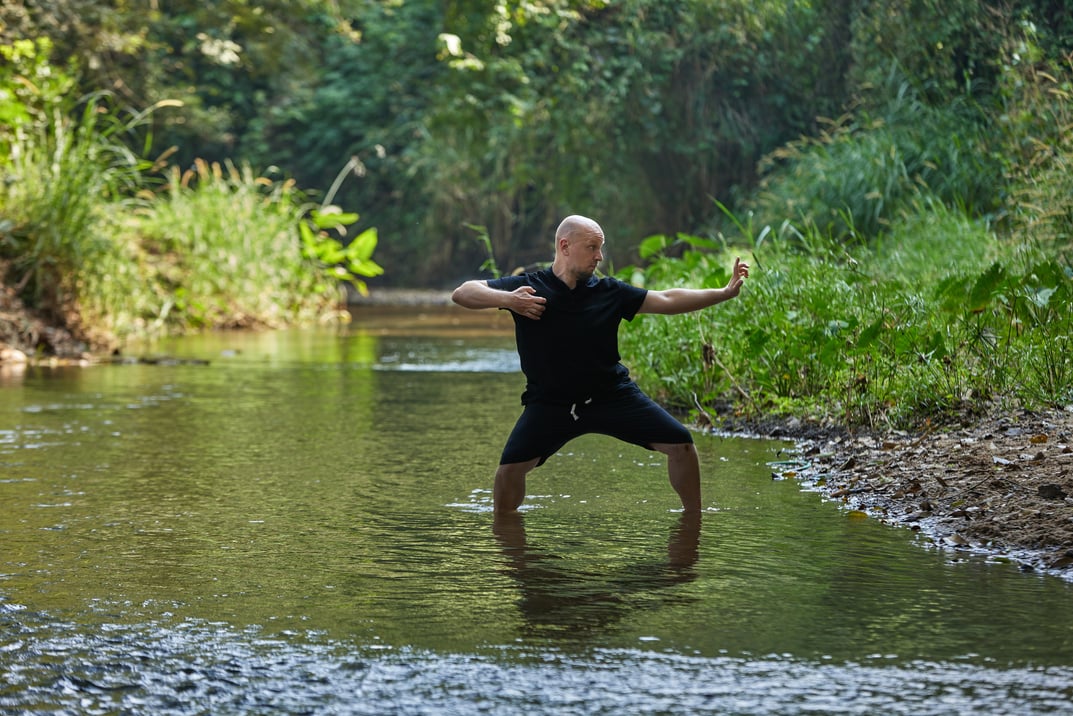 Practice makes perfect: A man performing qigong and taijiquan in a jungle river